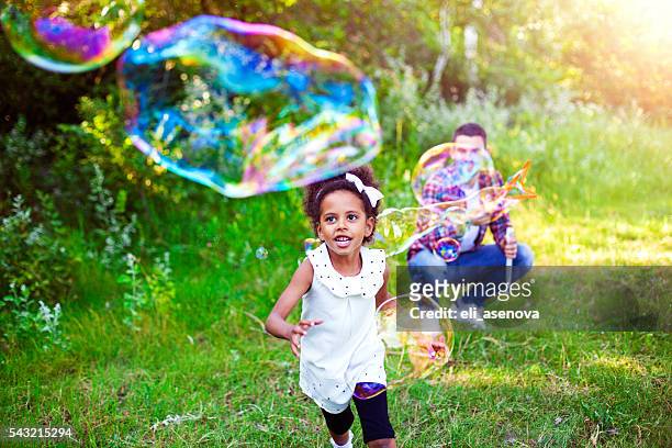 happy father and daughter playing soap bubbles in park. - bubbles happy stockfoto's en -beelden