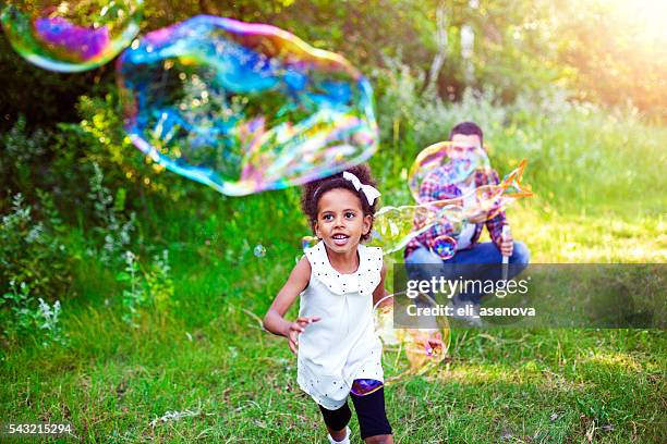 happy father and daughter playing soap bubbles in park. - mystical baby girls stock pictures, royalty-free photos & images