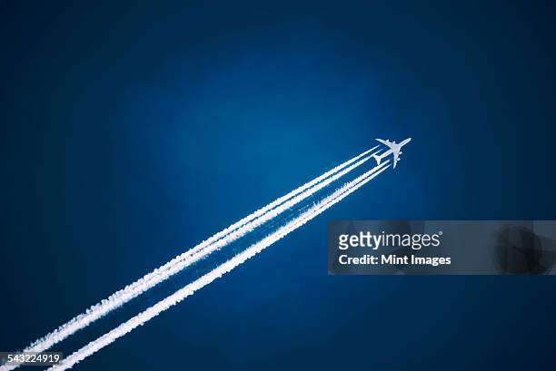 a jet vapour trail across a dark blue sky. - rastro de avião - fotografias e filmes do acervo