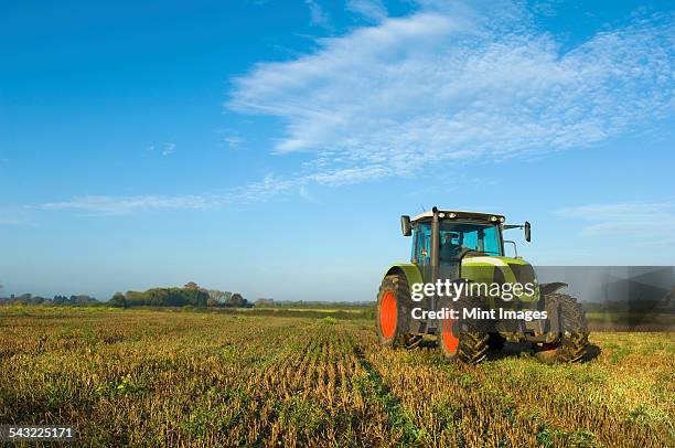 a tractor in a stubble field in gloucestershire. - trattore foto e immagini stock