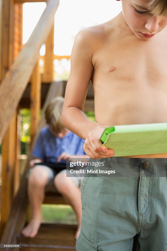 Two brothers playing on their digital tablets.