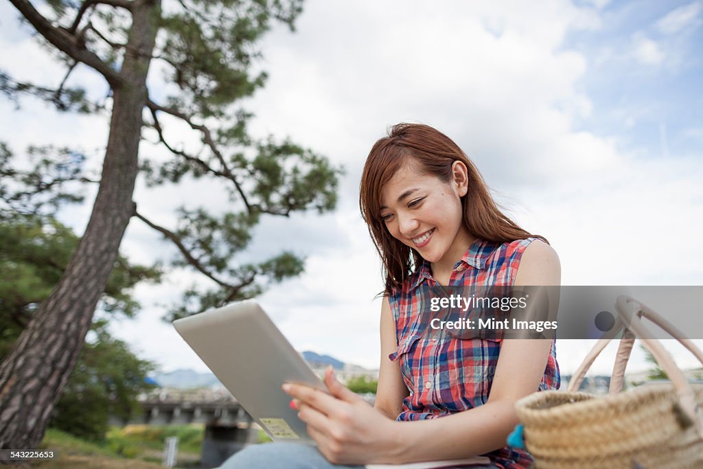 Young woman with a digital tablet in the park.