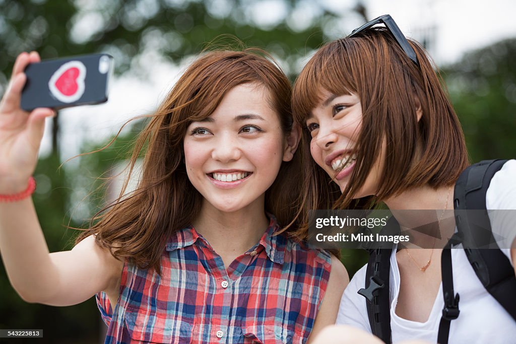 Two women, friends, taking a selfie in the park. 