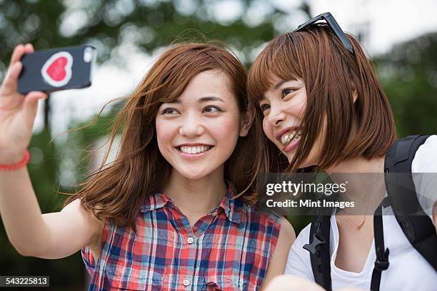 two women, friends, taking a selfie in the park.  - self portrait photography stock pictures, royalty-free photos & images