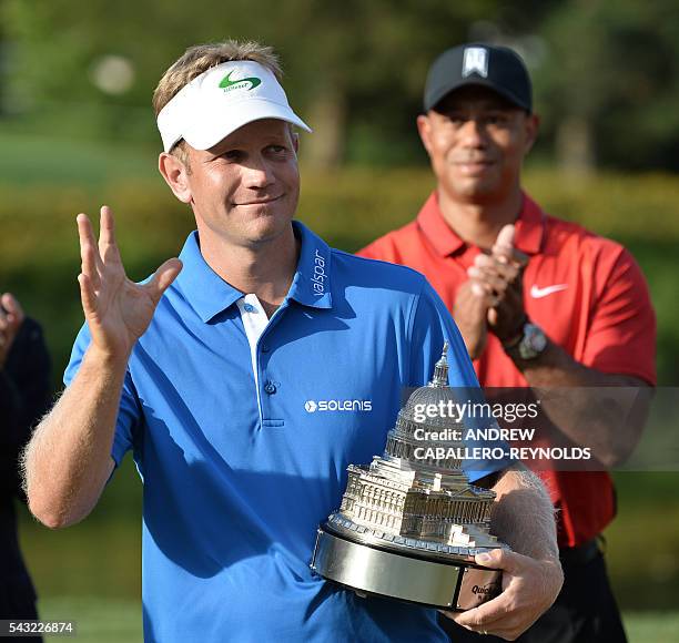 Billy Hurley III holds the trophy as Tiger Woods applauds after the final round of the Quicken Loans National at Congressional Country Club in...