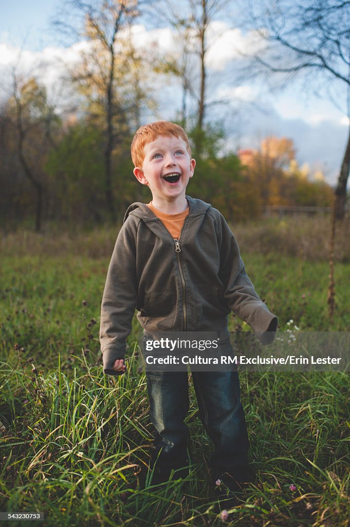 Portrait of red haired mischievous boy in field