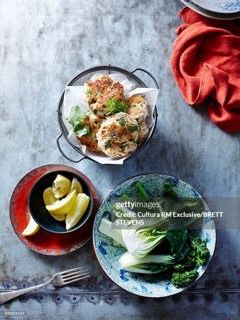 Still life of coconut fish cakes with broccoli and pak choi