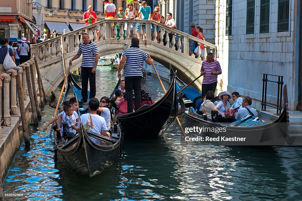 Gondolas carry tourists on the canals of Venice Italy. Some water ways get crowded in the summer.