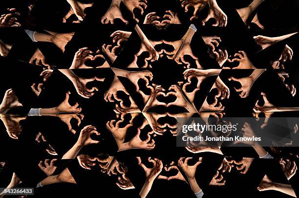 kaleidoscope image of hands forming heart shape - kaleidoskop stock-fotos und bilder