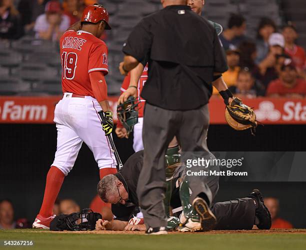 Jefry Marte of the Los Angeles Angels of Anaheim reacts as umpire Paul Emmel lies on the ground bleeding after being struck in the head with a bat...