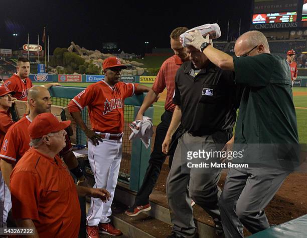 Umpire Paul Emmel is assisted off the field by athletic trainers Walt Horn of the Oakland Athletics and Adam Nevala of the Los Angeles Angels of...