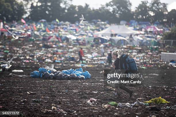 Departing festival goers pass rubbish left behind at the Glastonbury Festival 2016 at Worthy Farm, Pilton on June 26, 2016 near Glastonbury, England....