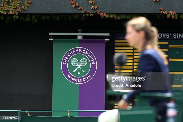 Woman passes by the logo of Wimbledon on day one of the 2016 Wimbledon Championships at the All England Lawn Tennis and Croquet Club in London,...
