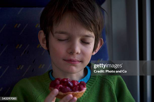 child eating a tart raspberry on the train - alleen jongens stockfoto's en -beelden