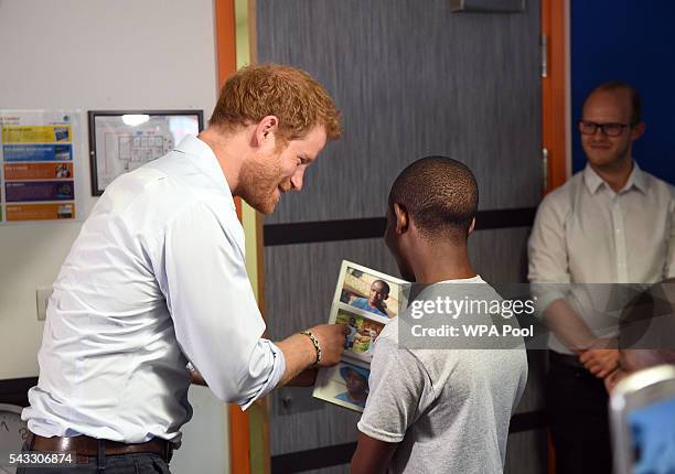 Prince Harry looks at photos with 16 year-old Relebohile 'Mutsu' Potsane after watching members of the Basotho Youth Choir during their rehearsals at...