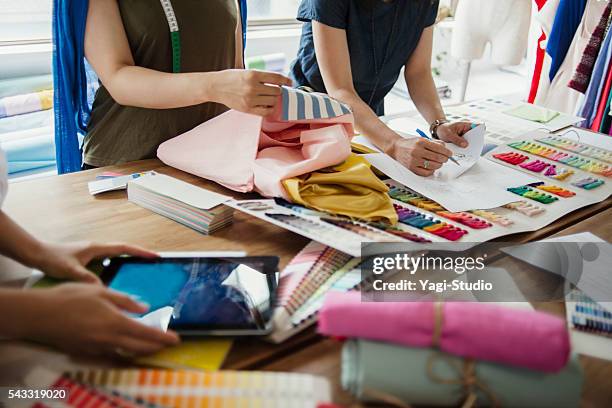 fashion designers working in studio - textielindustrie stockfoto's en -beelden