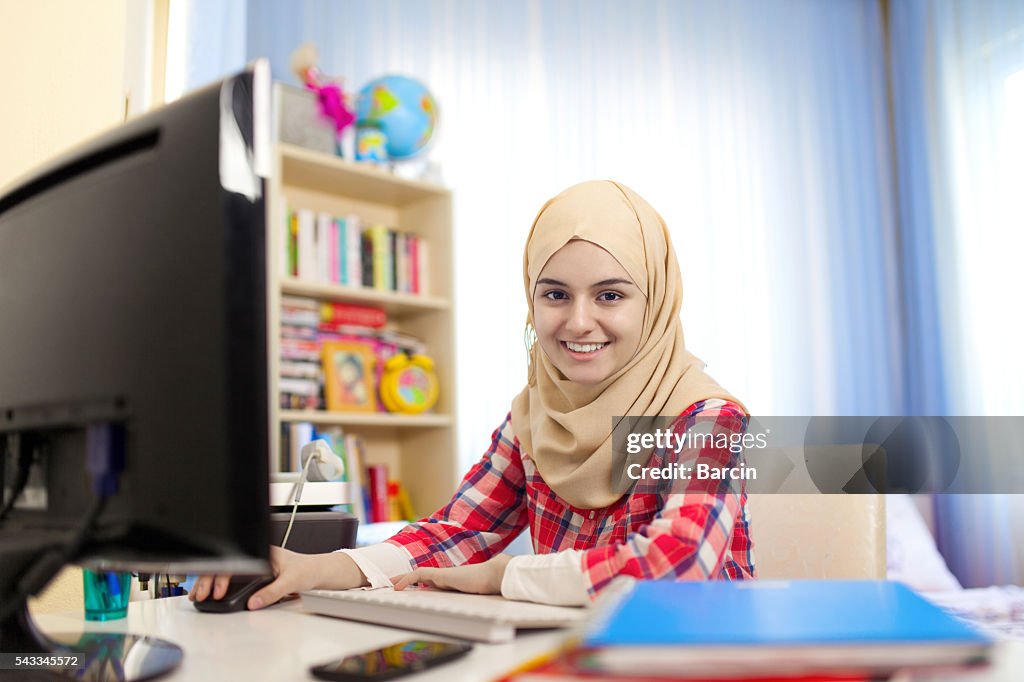 Teenage muslim girl working at home