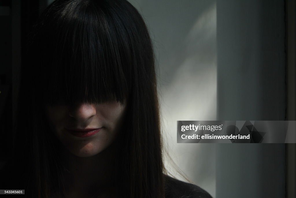 Portrait of young woman with fringe covering eyes