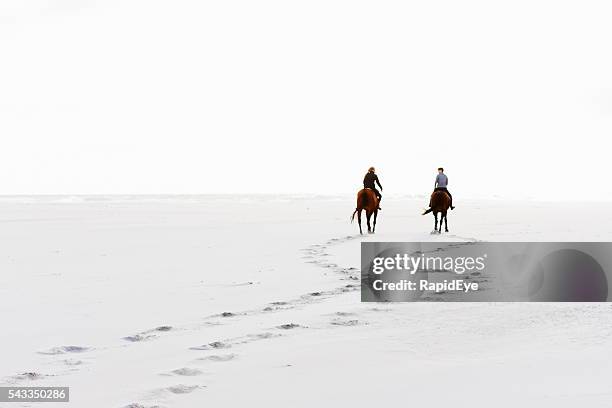 two horseriders leave hoofprints in the sand on winter day - trail ride stock pictures, royalty-free photos & images