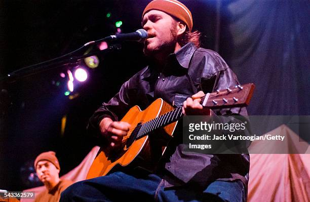 American musician Citizen Cope plays guitar as he performs onstage at the Hammerstein Ballroom, New York, New York, March 4, 2002. Behind him, Chris...