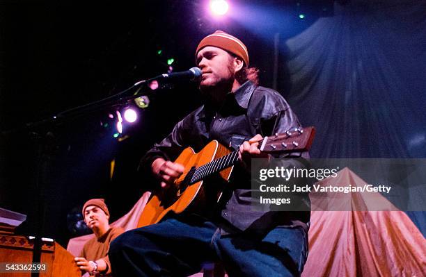 American musician Citizen Cope plays guitar as he performs onstage at the Hammerstein Ballroom, New York, New York, March 4, 2002. Behind him, Chris...