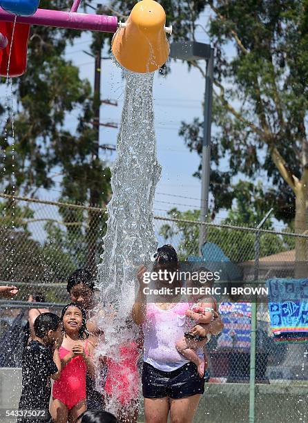 Parents and their children cool off at a water park on a hot summer day in Alhambra, east of downtown Los Angeles, California on June 27 where a hot...