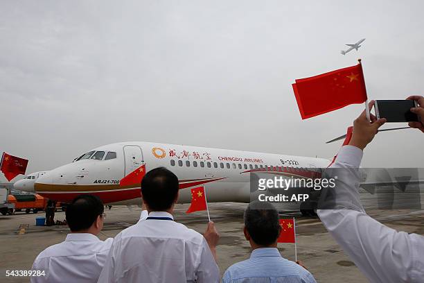 People wave Chinese flags as an ARJ21-700, China's first domestically produced regional jet, arrives at Shanghai Hongqiao Airport after making its...