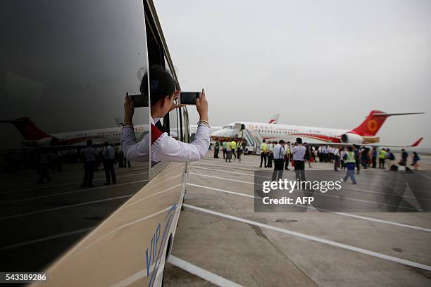 Woman takes pictures as an ARJ21-700, China's first domestically produced regional jet, arrives at Shanghai Hongqiao Airport after making its first...