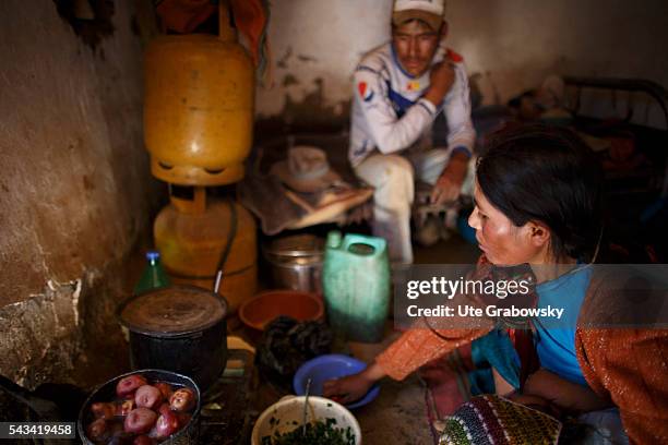 Tarwachapi, Bolivia A young woman is cooking in a humble cottage while breastfeeding her child. Her husband is waiting in the background for the food...