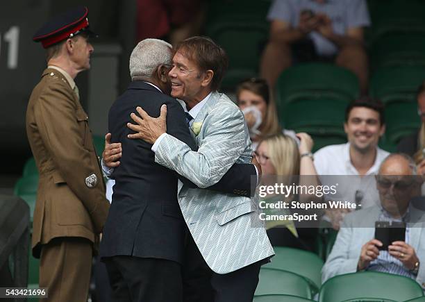 Cliff Richard and Sir Trevor McDonald, OBE greet each other in the members enclosure during his mens first round match against at Wimbledon on June...