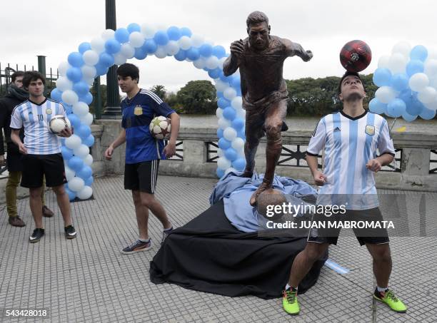 Young play with footballs next to a sculpture of Argentina's forward Lionel Messi, after it unveiling by Buenos Aires Mayor Horacio Rodriguez Larreta...