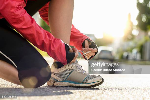 female runner tying shoe lace in a urban area - tied up stock pictures, royalty-free photos & images