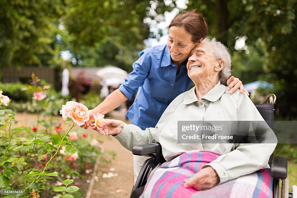 Senior Frau sitzt auf einem Rollstuhl mit Der Fürsorgliche