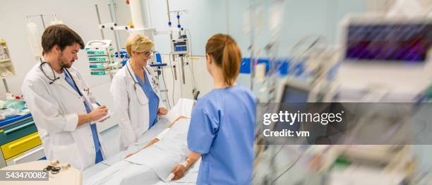 doctor's team beside injured pation's bed - er visit stock pictures, royalty-free photos & images