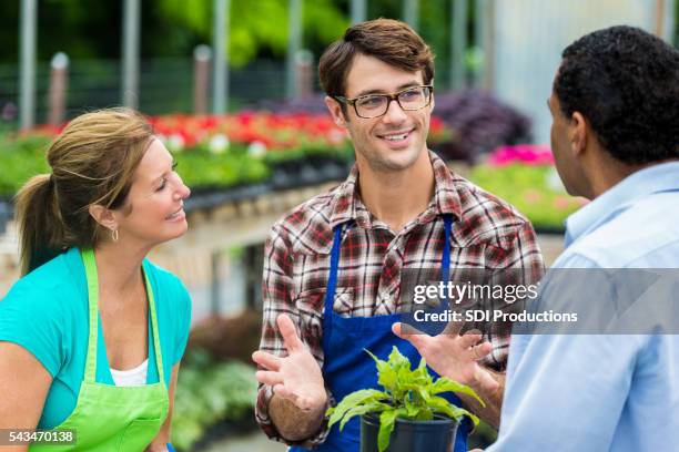 garden center employee answering customers questions - tuincentrum stockfoto's en -beelden