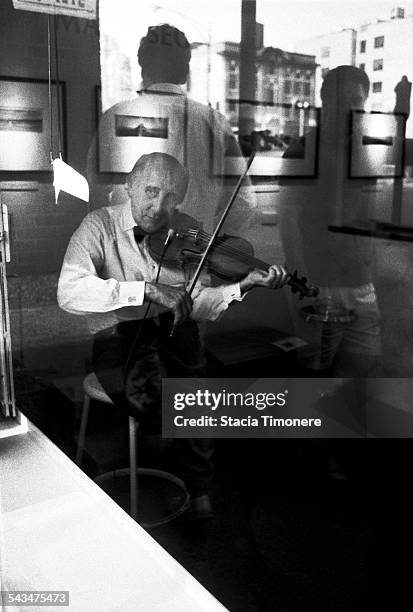 American jazz violinist and double bass player Johnny Frigo playing the violin in the window of a River North Art Gallery on Orleans St, Chicago,...