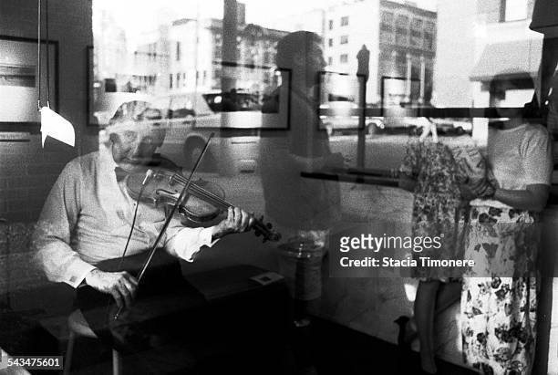 American jazz violinist and double bass player Johnny Frigo playing the violin in the window of a River North Art Gallery on Orleans St, Chicago,...