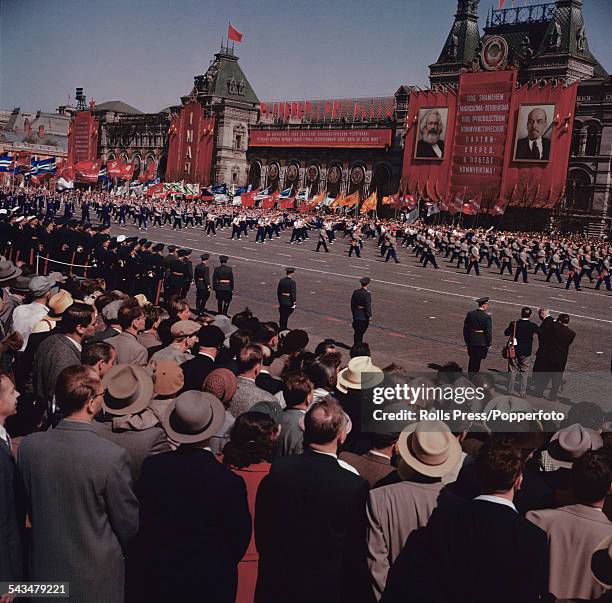 View of spectators watching participants carrying banners and flags march past the GUM store in Red Square, Moscow during a Soviet era May Day parade...