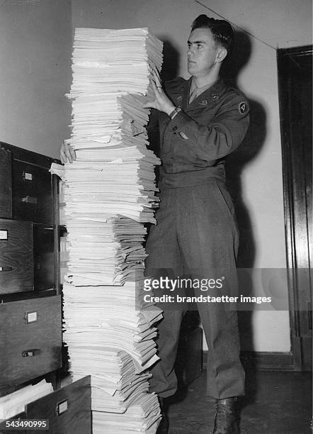 Nuremberg Trials. US Soldier Herbert Boe from the translation division holding a pile of transcripts representing a little part of the evidence for...