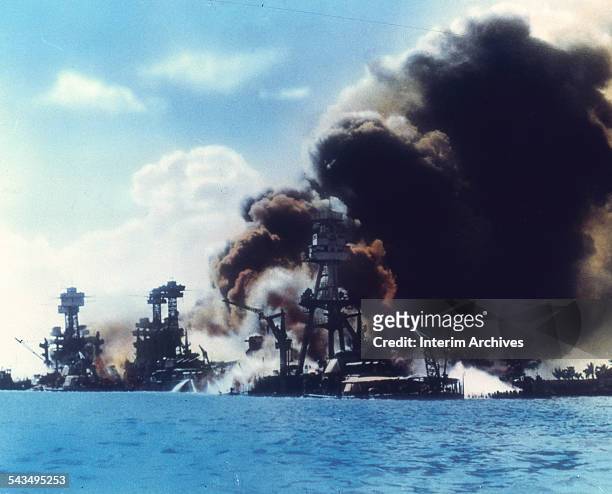 View of battleship row as explosions damage three American battleships during the Japanese attack on Pearl Harbor, Honolulu, Oahu, Hawaii, December...