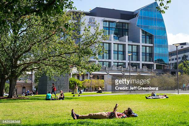 Australia, Victoria Melbourne Carlton Parkville University of Melbourne campus school University Square student man lawn reading relaxing School of...