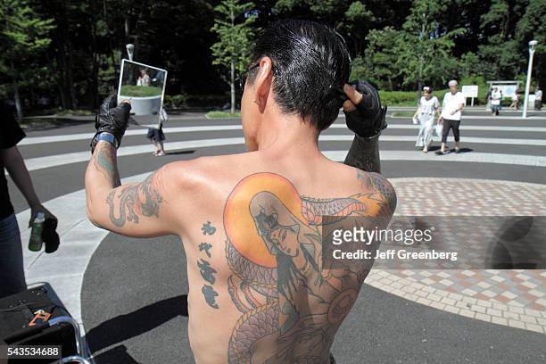 Japan Tokyo Harajuku Yoyogi Koen Park Asian man tattoo bare back cosplay costume play greaser Elvis motorcycle gang style hair c.
