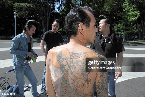 Japan Tokyo Harajuku Yoyogi Koen Park Asian man tattoo bare back cosplay costume play greaser Elvis motorcycle gang style hair.