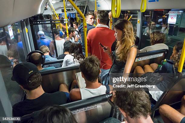 Australia, Sydney, public bus onboard riders passengers sitting standing woman smartphone.