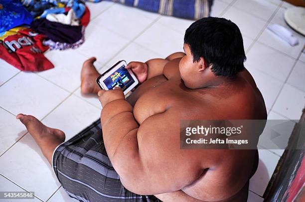 Arya Permana 10-year-old who weights 192 kilograms playing game in his tablet in his home on June 13, 2016 in West Java, Indonesia. A 10-YEAR-OLD...