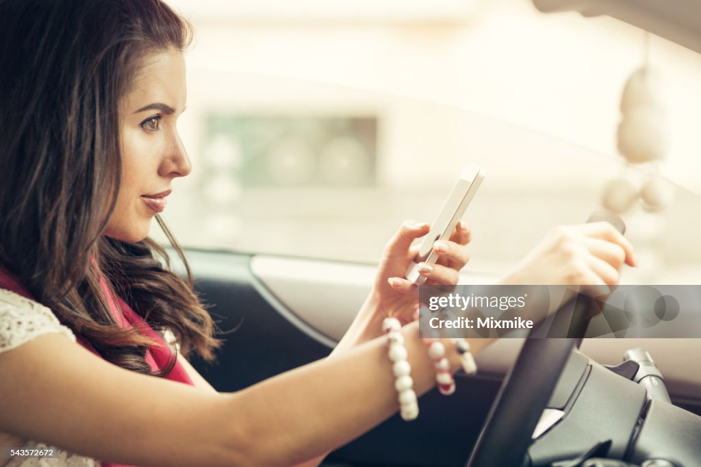 Woman texting on a cell phone in her car