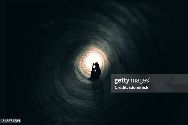 mujer en un lugar oscuro medida - luz al final del túnel fotografías e imágenes de stock