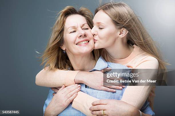 teenage daughter kisses mother on cheek. - mother and daughter kiss happy stock-fotos und bilder