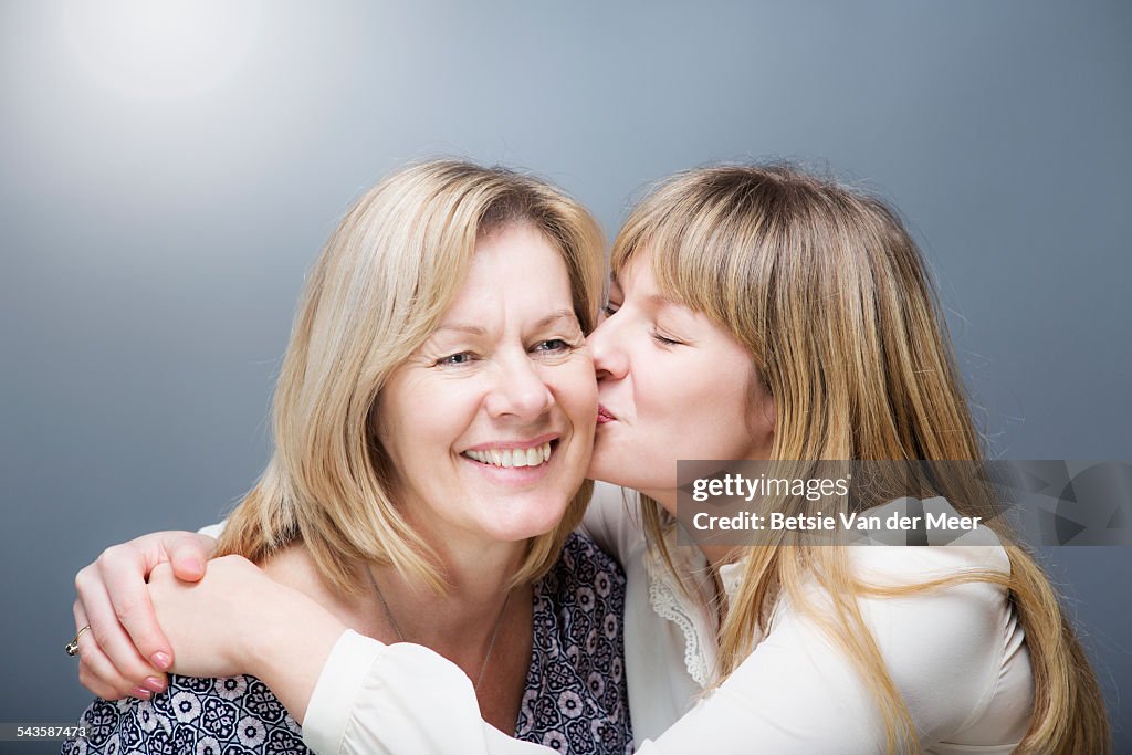 Daughter kisses mother on cheek.