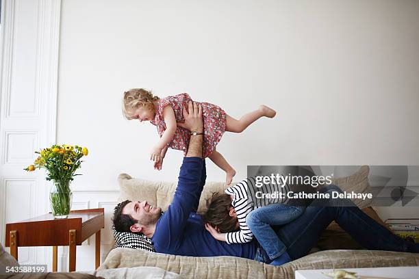 a dad playing with his children on a sofa - comfy pants stock pictures, royalty-free photos & images